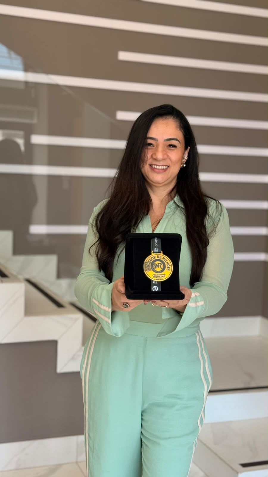 Lidiane Andrade segurando uma medalha de reconhecimento